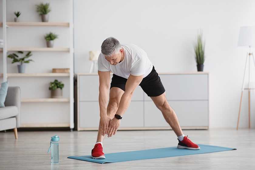 Woman performing morning full body stretching routine with arms raised, bright natural light